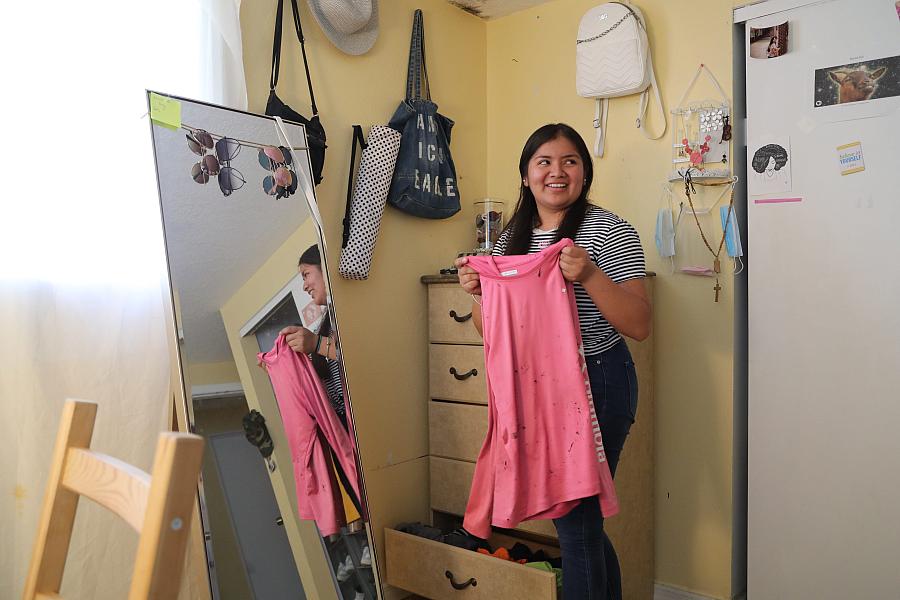 Luz Vazquez Hernandez, 18, pulls out the shirt she wore for roofing last summer. 