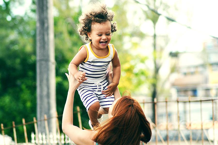 woman holding toddler girl up in the air