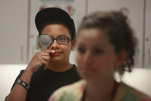Carlos, 14, takes an eye exam from medical aide Eneida Vera at the Oakland clinic. Photo: Lea Suzuki, The Chronicle