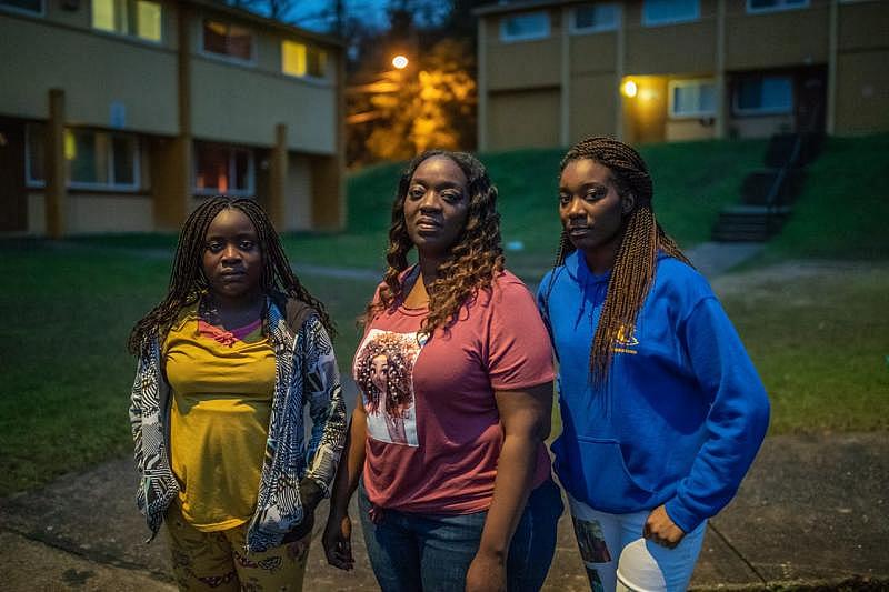 Kisha Simms, 38, center, poses with her daughters Deitra “DeeDee” Jackson, 11, and Lynaya “Naya” Saylor, 18, under the glow of a street light in their neighborhood, Springfield Apartments.