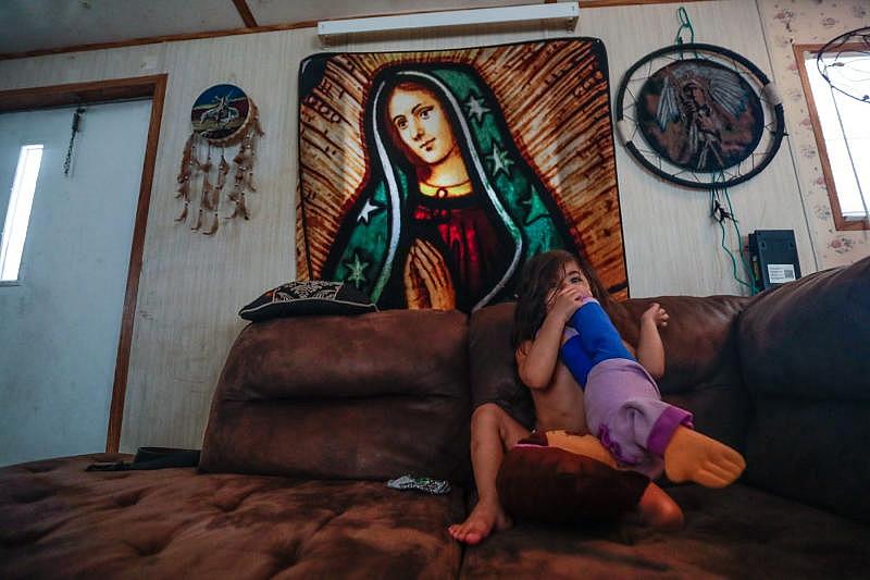 Victoria, 3, holds a large stuffed Dora the Explorer doll as she listens to her mom talk in the living room of their trailer off Aenon Church Road.