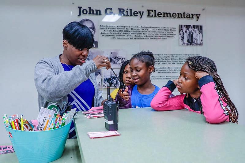 Riley Elementary School Principal April Knight hands out pencils and bookmarks to students who answered the daily Black History Month trivia question correctly.
