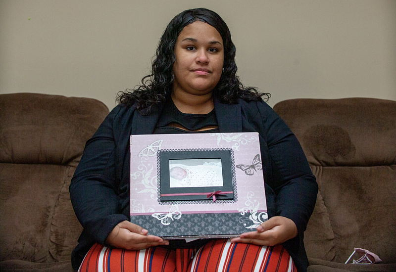 Nadia King's mother Martina Faulk, in her home on a couch, holds a photo album of her daughter's baby pictures. Will Brown