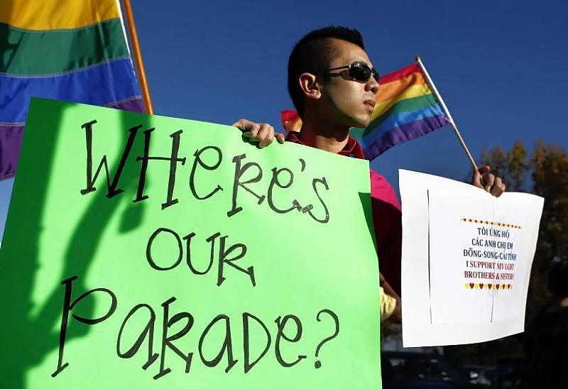 Minh Tran of Westminster holds a sign and Pride flag as he protests the exclusion of LGBT groups from the Tet parade in Little Saigon in 2013. (Allen J. Schaben / Los Angeles Times) Minh Tran of Westminster holds a sign and Pride flag as he protests the exclusion of LGBT groups from the Tet parade in Little Saigon in 2013. (Allen J. Schaben / Los Angeles Times)