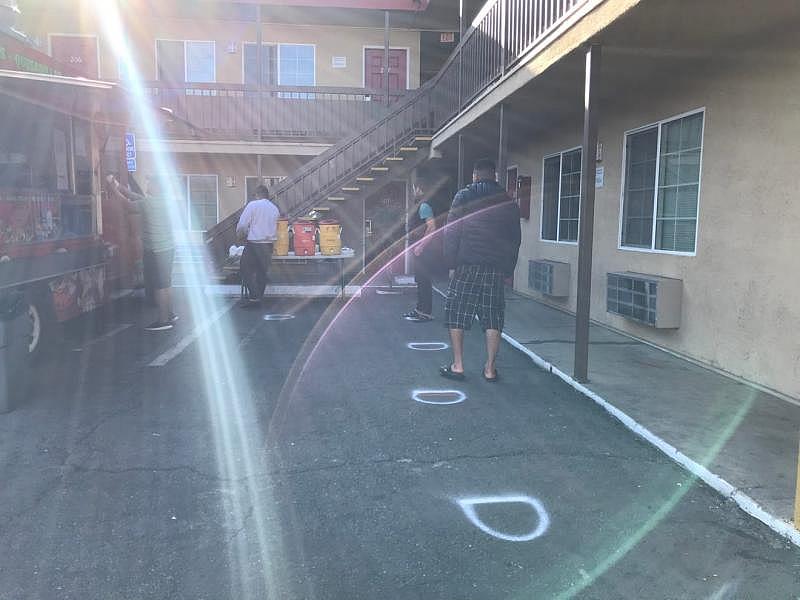 H-2A Foothill Packing workers gather in the evening for their dinner at the Budget Inn Motel on John Street, observing social distancing lines drawn on the pavement. April 13, 2020. Kate Cimini/ The Salinas Californian