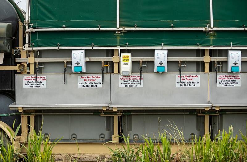 Sanitizers and soap dispensers are placed next to hoses of water that farmworkers use to wash their hands before and after picking strawberries and eating lunch in Watsonville, Calif. David Rodriguez/The Salinas Californian & Catchlight