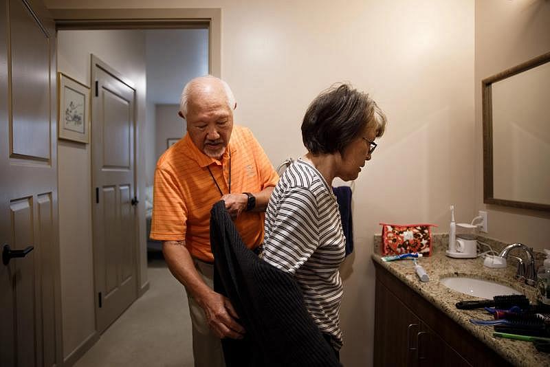 Fred Mekata helps his wife, Ruth, at her bedtime in their unit at The Watermark in July 2021. (Dai Sugano/Bay Area News Group) 