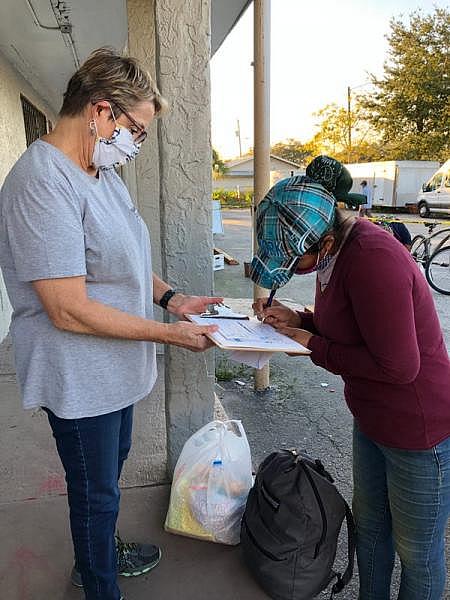 Ruth DeYoe of Mision Peniel in Immokalee requests the signature of a farmworker who is receiving financial help from the social services organizatioon in January 2021 after the woman's son tested positive for the coronavirus and she was unable to work. Janine Zeitlin/USA Today Network Florida