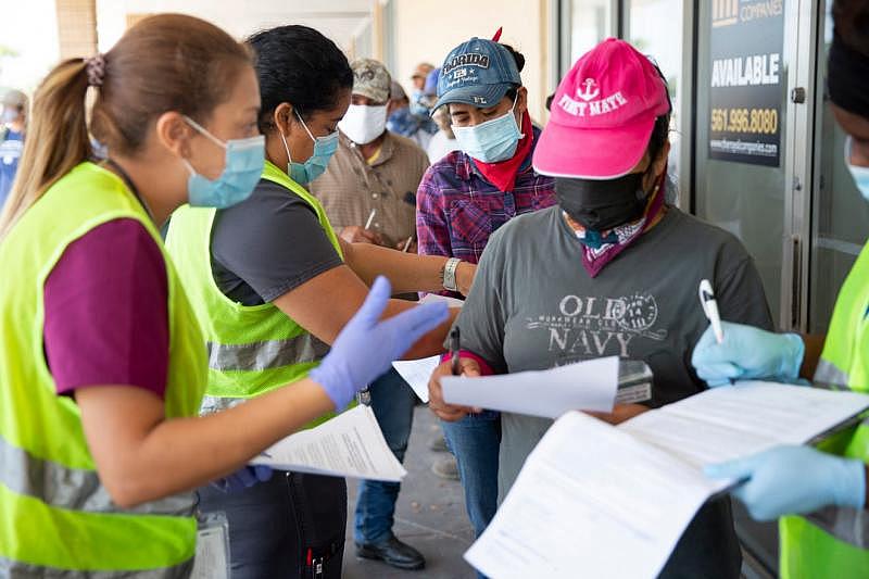 Healthcare Network employees help farmworkers fill out their paperwork as they wait in line during a vaccine clinic for farmworkers at the Florida Department of Health in Collier County site on Lake Trafford Road in Immokalee on Saturday, April 10, 2021. Alex Driehaus/Naples Daily News/USA TODAY - FLORIDA NETWORK