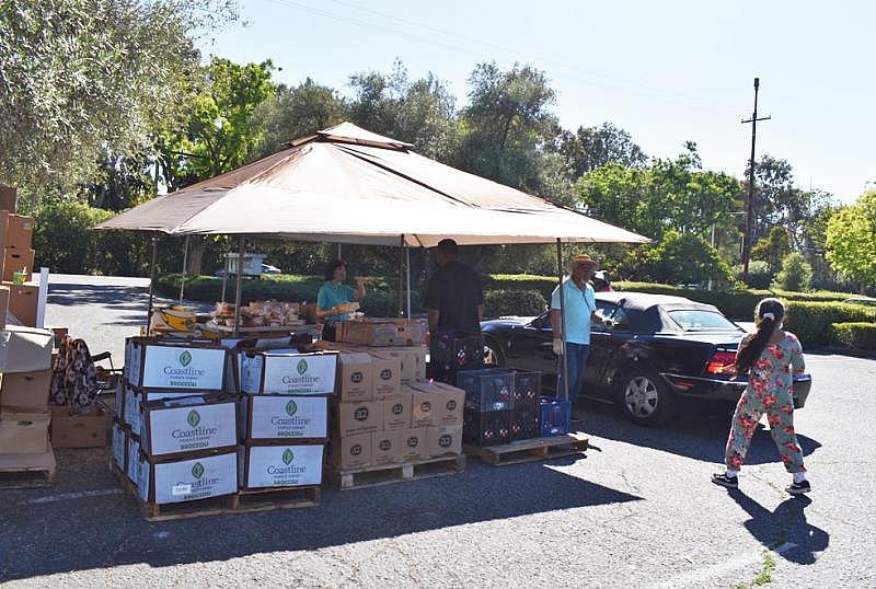 Volunteers help load boxes of food into vehicles after asking drivers how many boxes of food they want on June 4, 2021, at a food distribution site in Palo Alto. Photo by Kate Bradshaw.