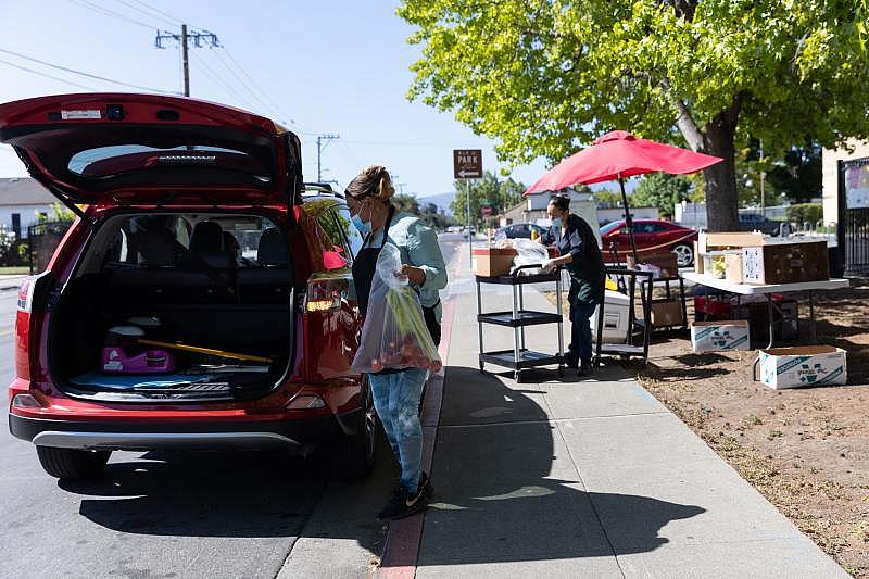 Irma Muñoz places bags of food in a client's car at a food pick-up site at the Los Robles Ronald McNair Academy in East Palo Alto on May 19, 2021. Photo by Magali Gauthier. Irma Muñoz places bags of food in a client's car at a food pick-up site at the Los Robles Ronald McNair Academy in East Palo Alto on May 19, 2021. Photo by Magali Gauthier.