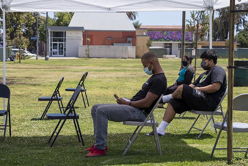 Freshly vaccinated individuals sit for about 15 minutes after receiving a one-dose during a mobile vaccine clinic at the rear of MacArthur Park in Central Long Beach on Tuesday, May 25, 2021. Photo by Crystal Niebla.