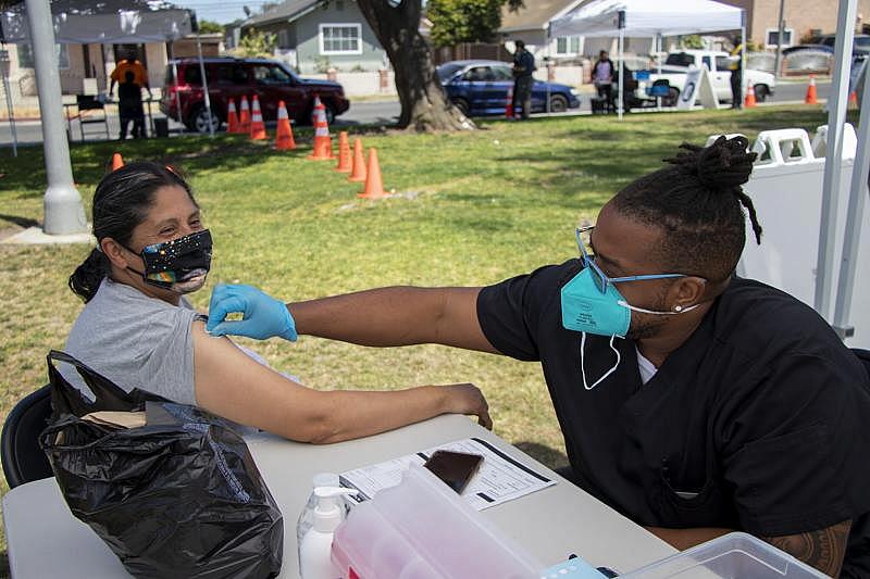 Darren Grant, right, prepares the arm of 58-year-old Rosa Sandoval, left, for a COVID-19 vaccine during a mobile vaccine clinic at  MacArthur Park in Central Long Beach on Tuesday, May 25, 2021. Photo by Crystal Niebla.