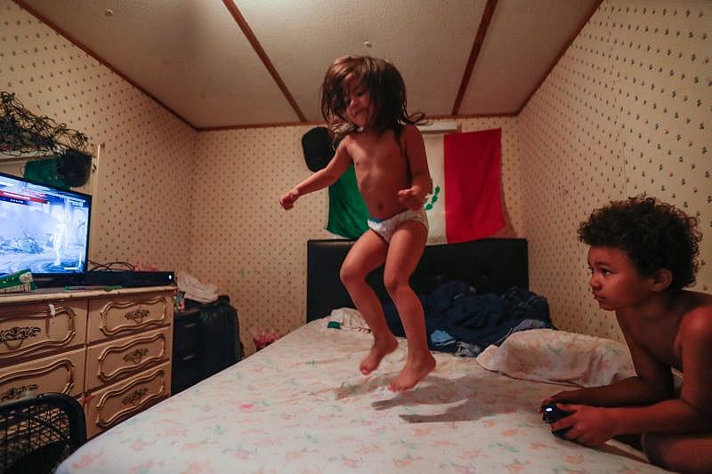 Victoria, 3, jumps on her mom's bed while her 8-year-old brother Romeo plays Xbox games. The siblings live with their mom, her younger sister, and their mom's husband. ALICIA DEVINE/TALLAHASSEE DEMOCRAT