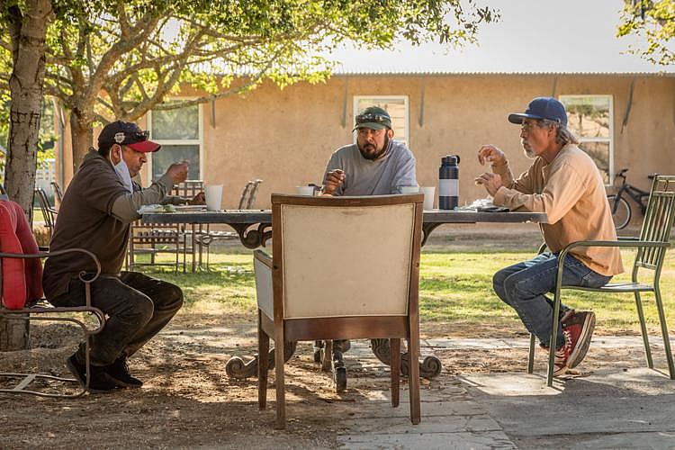 Jose Segura, left, eats dinner with his fellow River Ranch residents. Neither Segura nor his wife or daughter have health insurance because the employer-offered and private-payer premiums are too costly for them to afford, Segura said, but he and his wife make too much annually to qualify for MediCal.  Clark James Mishler