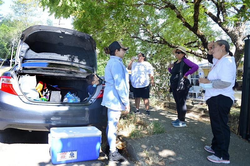 Lucy Tafoya (left), a promotora, hands out water and talks with fellow promotoras Diana Gomez Martinez, Chela Botello and a participant at the ‘10,000 Steps’ event in Willits on June 26 2021. Dana Ullman / The Mendocino Voice Lucy Tafoya (left), a promotora, hands out water and talks with fellow promotoras Diana Gomez Martinez, Chela Botello and a participant at the ‘10,000 Steps’ event in Willits on June 26 2021. Dana Ullman / The Mendocino Voice