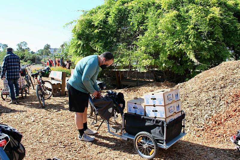 A volunteer adjusts something on a bicycle before setting out to make food box deliveries through the Eastside Connect program on May 1, 2021. Courtesy Silicon Valley Bicycle Coalition. A volunteer adjusts something on a bicycle before setting out to make food box deliveries through the Eastside Connect program on May 1, 2021. Courtesy Silicon Valley Bicycle Coalition.