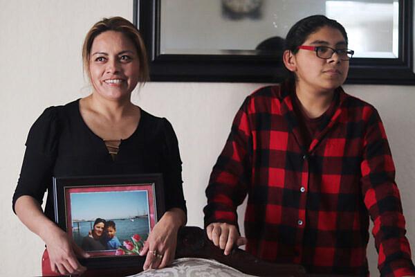 Fabiola Aguilar poses for a photo alongside her 14-year-old son Bryan in there home in San Francisco's Bayview neighborhood. The photo Fabiola is holding is of herself and her eldest son, Gael, who both migrated to San Francisco 19 years ago. Photo: Alexis Terrazas