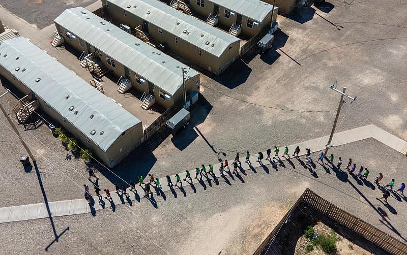 Endeavors employees escort a line of teenage boys at a migrant children’s emergency center in Pecos, Texas, in October 2021. Credit: Nick Wagner/San Antonio Report