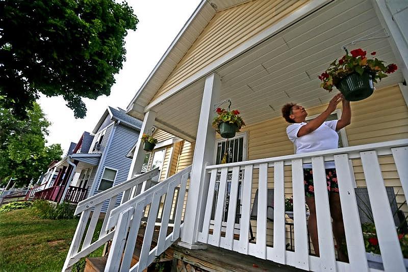 Delisa Scott prunes potted flowers on her porch in the 2000 block of N. 25th Street. Children who live in 53205, a predominately Black ZIP code on Milwaukee’s near north side, visit the emergency department for asthma 20 times more than children living just a 15-minute drive away in the predominately white suburb of Whitefish Bay. ANGELA PETERSON / MILWAUKEE JOURNAL SENTINEL