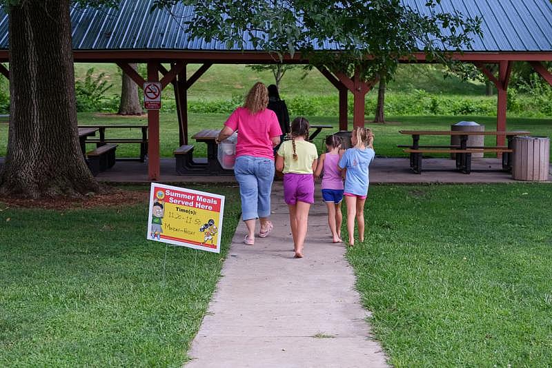 Children follow as Christina Pinkerton and Shannon Bundridge take food for the summer meals program to the picnic area in Kirksville, Mo., on Aug. 16. Arin Yoon for NBC News