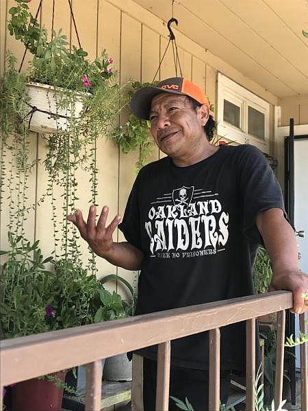 Guillermo Hernandez, a maintenance worker and renter, stands outside of his second-story apartment amidst his plants. The greenery stands out against an otherwise dry, tan-colored landscape.