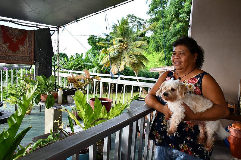 Rose Sylvia San Nicolas describes how Tinian is different from Saipan as she holds her dog outside her apartment where she has been living on Saipan for over a year. She grows Chamorro medicinal plants such as korason gala on her lanai.