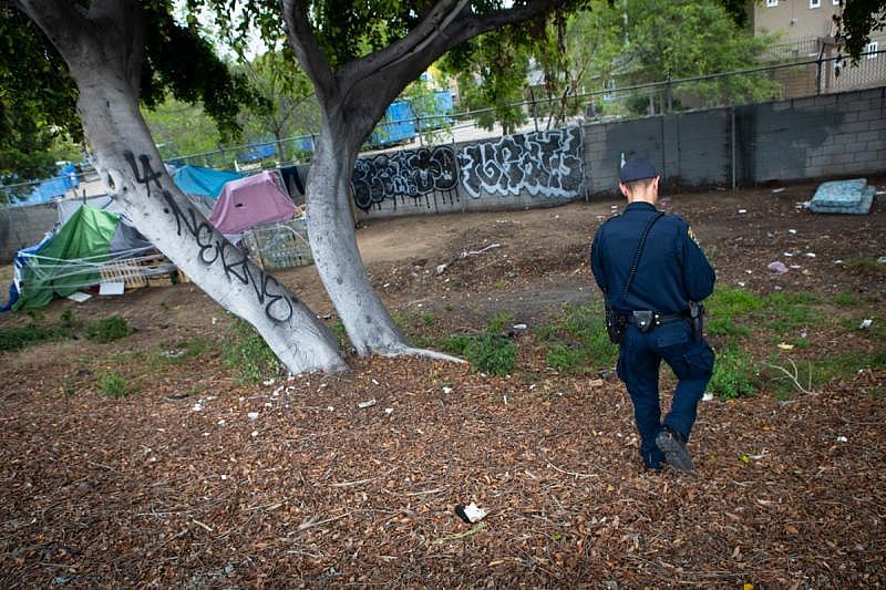 California Highway Patrol Officer Jesse Matias approaches an encampment along the side of the freeway in San Ysidro, April 28, 2022. Like other law enforcement agencies, the Highway Patrol responds to mental health crisis calls and may transport individuals to hospitals for possible involuntary holds if an officer determines they meet criteria. (Zoë Meyers/inewsource)