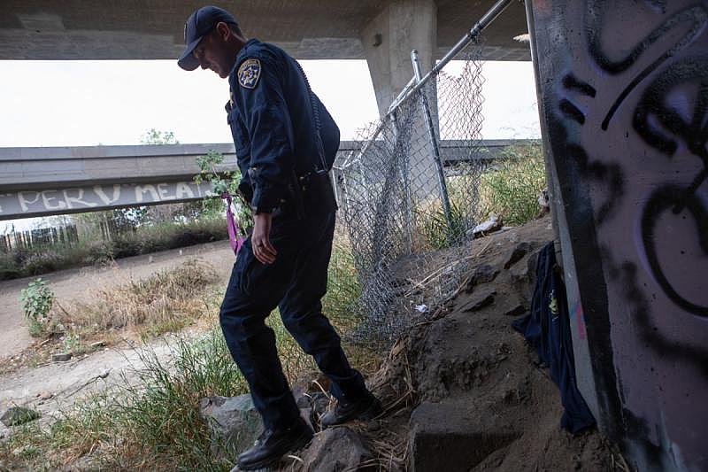 California Highway Patrol Officer Jesse Matias looks for individuals living under freeway ramps in Mission Valley, April 28, 2022. Like other law enforcement agencies, the Highway Patrol responds to mental health crisis calls and may transport individuals to hospitals for possible involuntary holds if an officer determines they meet criteria. (Zoë Meyers/inewsource)