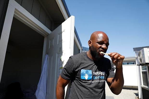 Henderson brushes his teeth in front of his tiny home before leaving for work on Tuesday, July 12, 2022. The Mabury tiny home site has a separate bathroom building for people living there. (Shae Hammond/Bay Area News Group)