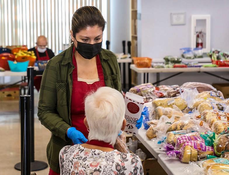 Community outreach coordinator Laura Gutierrez talks with a volunteer at the Cathedral City Senior Center food bank in Cathedral City, Calif., Monday, April 25, 2022. Andy Abeyta/The Desert Sun