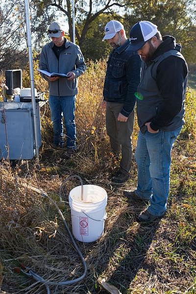 Water resources technicians Josh Schnitzler, left, and Connor Baldwin, right, and assistant general manager Brian Bruckner, center, who all work for the Lower Elkhorn Resources District in Norfolk, test the water in a monitoring well near the north fork of the Elkhorn River. These wells, located roughly 10 miles northwest of Elkhorn, are used to monitor ground water for nitrates and other substances like solids and sulfates. Photo by Ryan Soderlin for the Flatwater Free Press