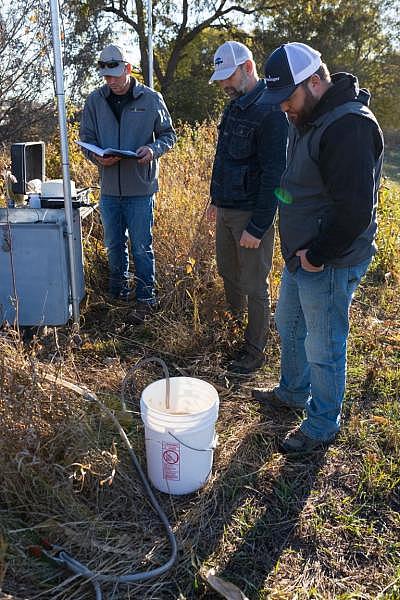 Water resources technicians Josh Schnitzler, left, and Connor Baldwin, right, and assistant general manager Brian Bruckner, center, who all work for the Lower Elkhorn Resources District in Norfolk, test the water in a monitoring well near the north fork of the Elkhorn River. These wells, located roughly 10 miles northwest of Elkhorn, are used to monitor ground water for nitrates and other substances like solids and sulfates. Photo by Ryan Soderlin for the Flatwater Free Press Water resources technicians Josh Schnitzler, left, and Connor Baldwin, right, and assistant general manager Brian Bruckner, center, who all work for the Lower Elkhorn Resources District in Norfolk, test the water in a monitoring well near the north fork of the Elkhorn River. These wells, located roughly 10 miles northwest of Elkhorn, are used to monitor ground water for nitrates and other substances like solids and sulfates. Photo by Ryan Soderlin for the Flatwater Free Press