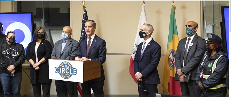 In November 2021, Los Angeles mayor Eric Garcetti (at podium), Urban Alchemy CEO Lena Miller (far left), and others unveil a UA-led program to send an unarmed outreach team instead of police to handle some non-emergency 911 calls.
