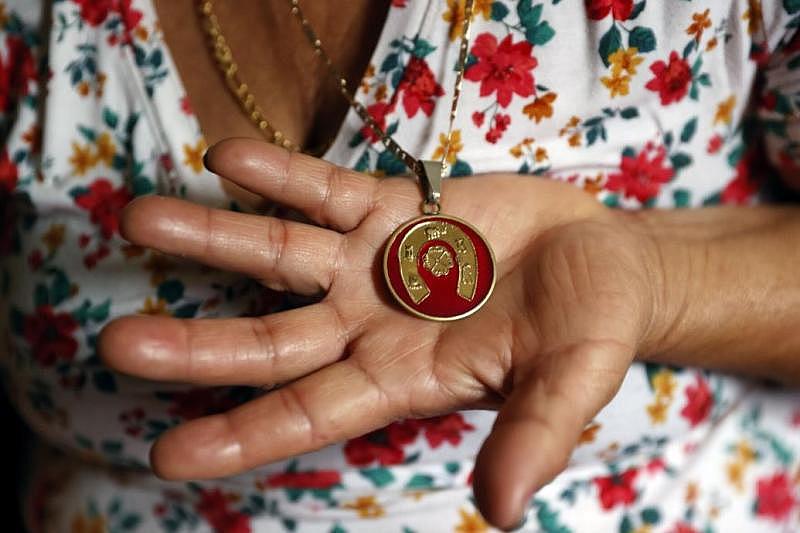 Maria Fuentes holds a pendant that was her husband's. Yuki Mendez died of COVID-19 at Chippenham Hospital on July 28, 2020. He was 40.  Photos by Eva Russo/Times-Dispatch