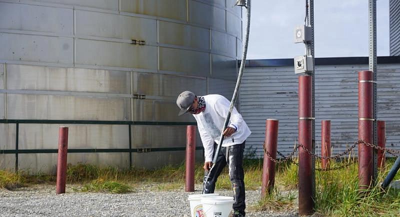 Zack Kitkon fills buckets with water from a supply provided by the city of Teller for 50 cents per gallon. Households in unserved and underserved communities in rural Alaska often make do with much less water than health experts recommend. (Yereth Rosen)
