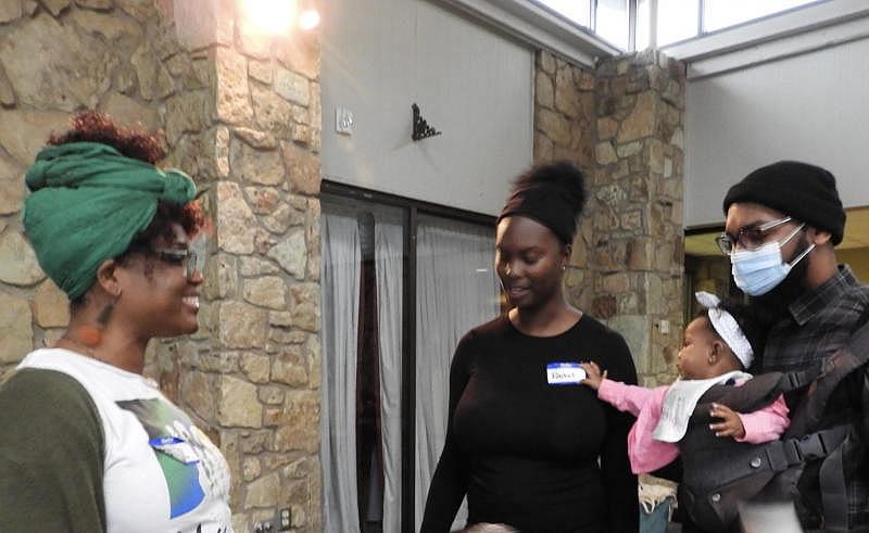 For the Village Executive Director Farah Antoine-Mayberry, left, talks with parents Rachel and Scott Nelson with daughter Gianna, 6 months, at an outreach event in Oklahoma City. BRIANNA BAILEY/The Frontier