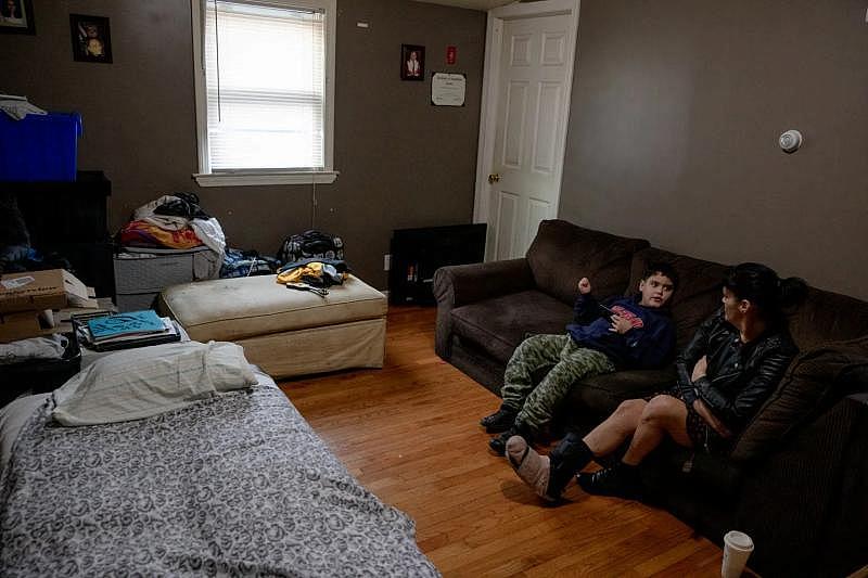 Elizabeth Rodríguez y Mikey se sientan en la sala de estar de la casa de su hermana, rodeados de sus pertenencias. Tuvo que tirar muchas pertenencias importantes después de los daños causados por la lluvia durante el desalojo. YEHYUN KIM / CT MIRROR