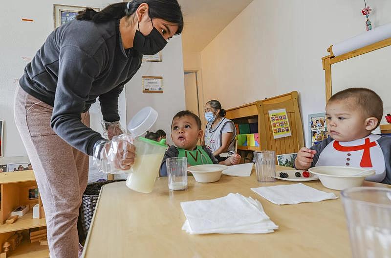 Assistant teacher Karina Palomino, left, pours milk for Julian and Ares, both one year old.(Eduardo Contreras / The San Diego Union-Tribune)
