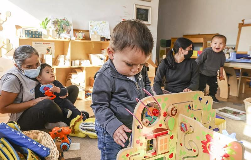 Julian plays with a toy as Miren Algorri’s assistant teachers play with the other children.(Eduardo Contreras / The San Diego Union-Tribune)