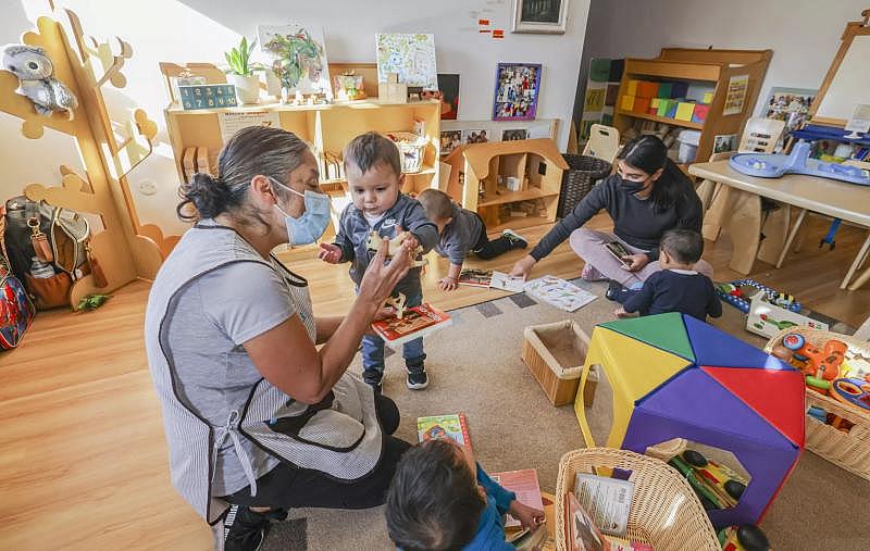 One-year-old Julian, standing, plays with Lucy Arevalo as the other children play on the floor.(Eduardo Contreras / The San Diego Union-Tribune)