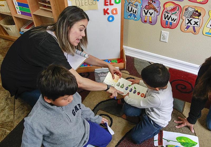 La especialista en apoyo a la calidad de YMCA Childcare Resource Service, Marlene Fuentes, trabaja con niños en casa de un proveedor de cuidado infantil en 2019, en Vista. Los expertos recomiendan a los padres visitar primero en persona un programa de cuidado infantil para ver cómo interactúan los proveedores con los niños.(Eduardo Contreras / The San Diego Union-Tribune)