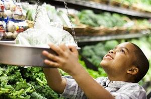 Boy weighing fresh produce at a grocery store.