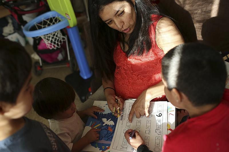 Jessica Sepulveda helps her son Xavier, 5, with his homework as her son Joshua, 2, watches at their apartment in San Antonio. Sepulveda said if she had had insurance when she got pregnant, she would have been able to see a doctor sooner.