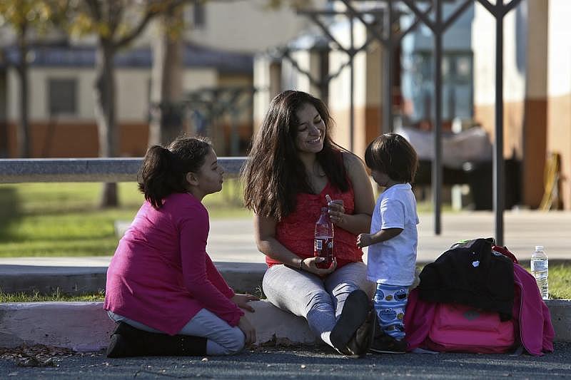 Jessica Sepulveda talks with her children, Joshua, 2, and Francesca, 11, as they play with their brother and cousins on the playground outside their apartment in San Antonio. Sepulveda is one of thousands of pregnant women in Bexar County to get late prenatal care.