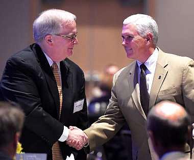 Indiana Gov. Mike Pence, right, greets Carl Chapman, chief executive of the Evansville-based utility company Vectren Corp. Mike Lawrence/Evansville Courier & Press