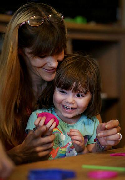 Christine Haley and daughter Lyns Wilson, 2, squish a ball of Play-Doh during a Healthy Families visit. Seventy-five percent of state funds for the program have been cut since 2009.