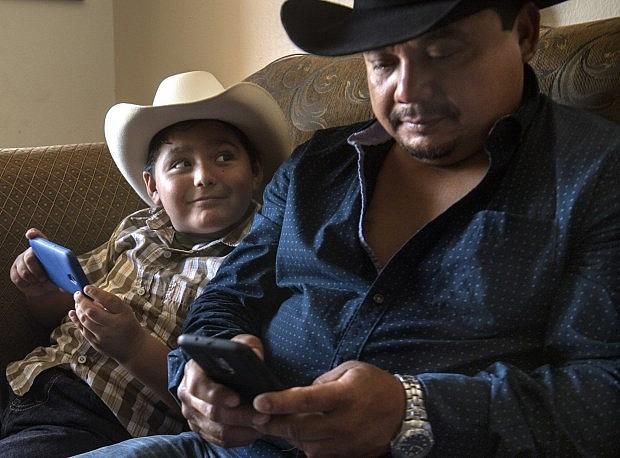 Hugo Secundino still struggles with the pain of losing his 14-year-old son, Angel, to gang violence in 2006. He recognizes mistakes he made with Angel and now wants to be a better, more attentive parent to his children, he says. A bull rider himself, he watches bull riding videos with his 7-year-old son on Saturday, July 29, 2017.