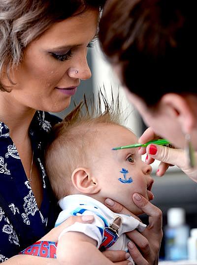 A 2016 ceremony at the Hall of Justice in Lansing, Mich., honored parents and kids with a day of face-painting and other fun. Here, Rowan is held still by Theresa McGill. Dave Wasinger / Lansing State Journal