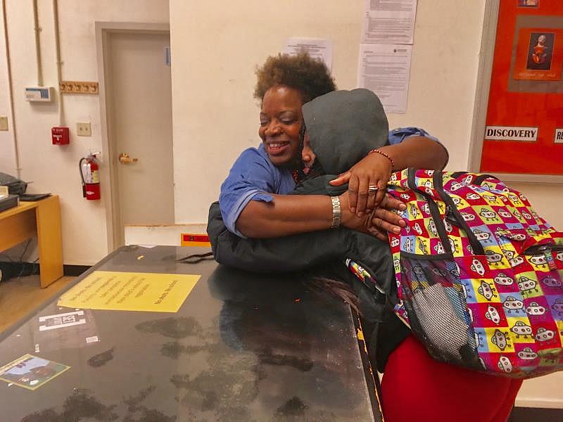 Destiny Shabazz, 17, gets a hug from a front office administrator at West Oakland’s McClymonds High School. Destiny has no parent or legal guardian. She’s not in foster care, and she’s not emancipated. (Lee Romney/KQED)